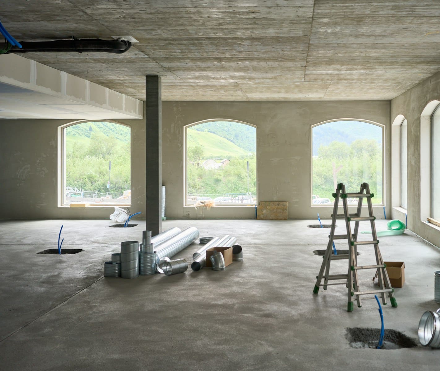 A wide, bright room with arched windows, cleared and prepared for abatement