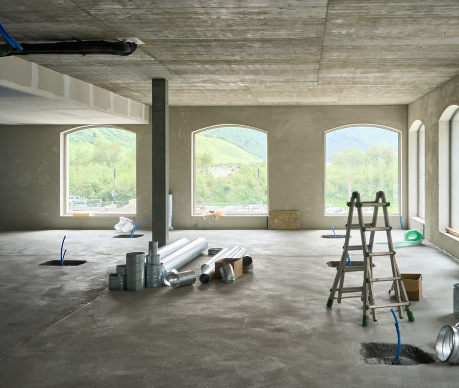 A large room with arched windows, prepared for work with a ladder and supplies